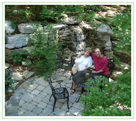 Satisfied customers sitting at wrought iron table on flagstone patio beside waterfall